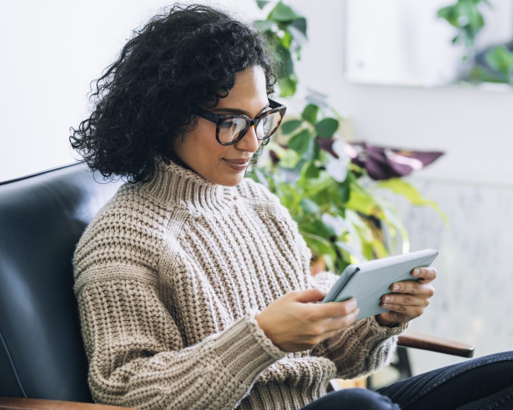 Woman in cozy sweater meets with a home visitor virtually using a tablet