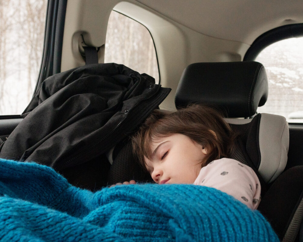 Young girl in unhoused family sleeps in their car