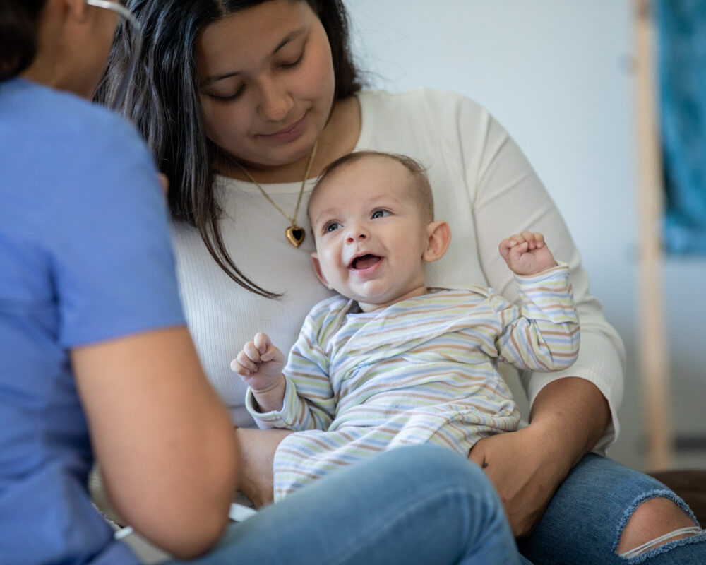 Woman chats with new mom and baby as part of her home visiting job