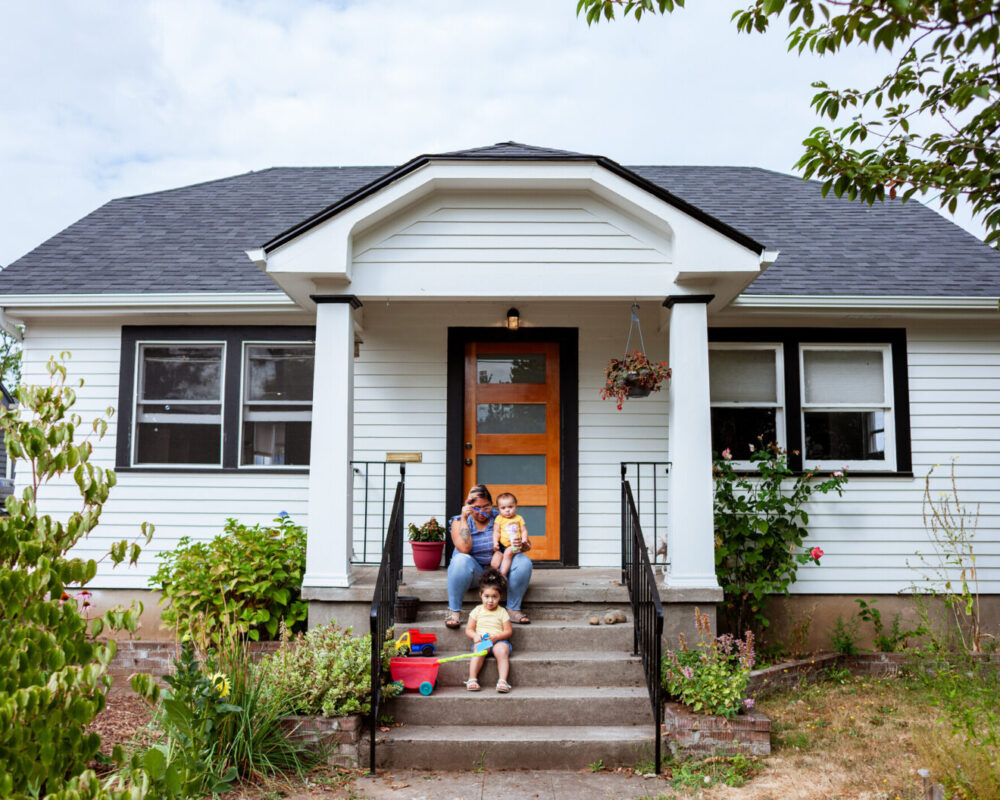 A mom playing with her two daughters while relaxing on the front porch.
