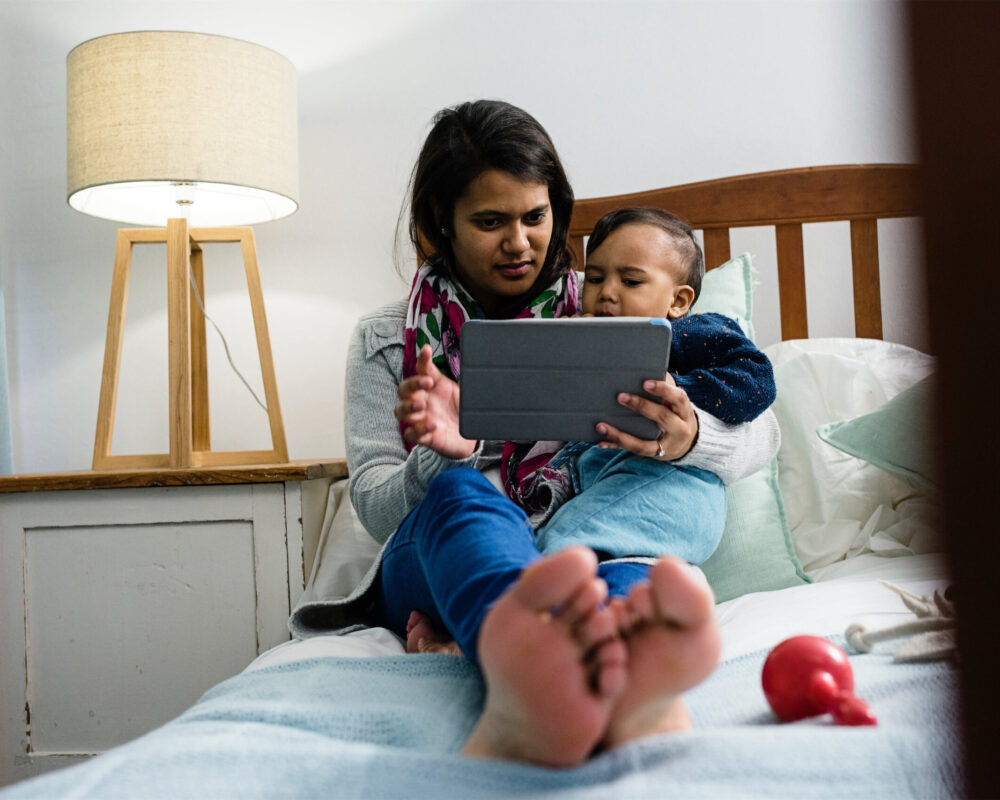 Mother and baby use a tablet to connect with their home visitor