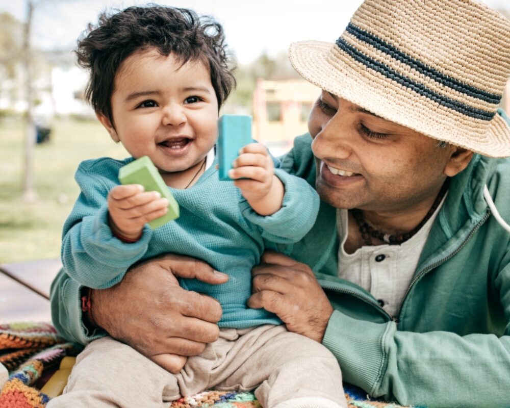 Father and son play together with blocks outdoors