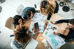 Work team sits around pages of charts and graphs at a conference table