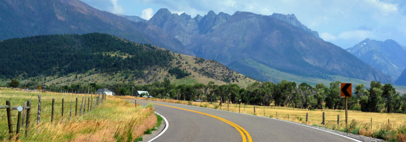 Empty rural road runs through the base of mountains