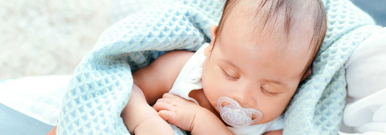 infant snuggles in blue blanket