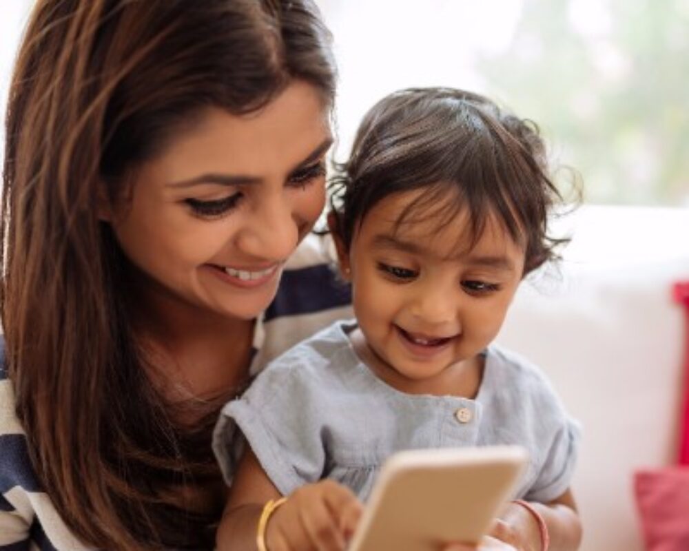 Mom and toddler smile at iphone screen together
