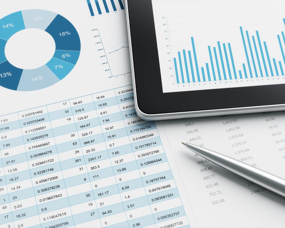 Tablet displaying an abstract chart rests on top of a printed chart and pen