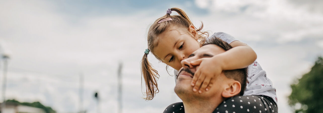 young girl sits on dad's shoulders
