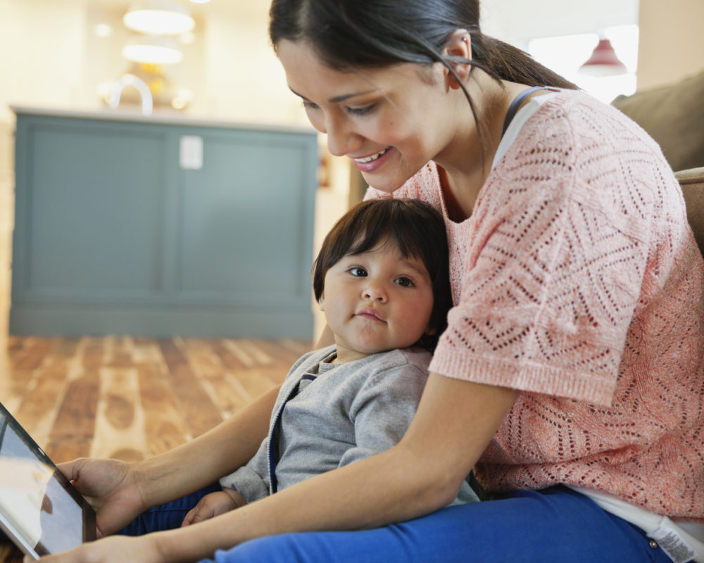 Baby sitting with mom using digital tablet